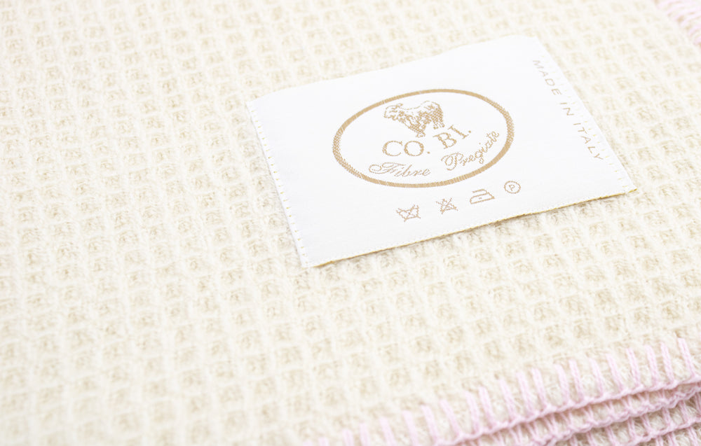 Particolare coperta di lana a nido d'ape bianca con bordo rosa