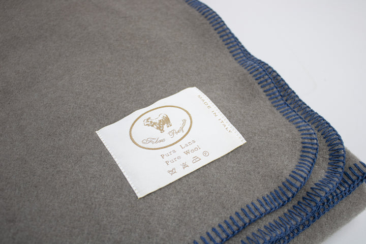Particolare plaid di lana color grigio fumo e bordo blu