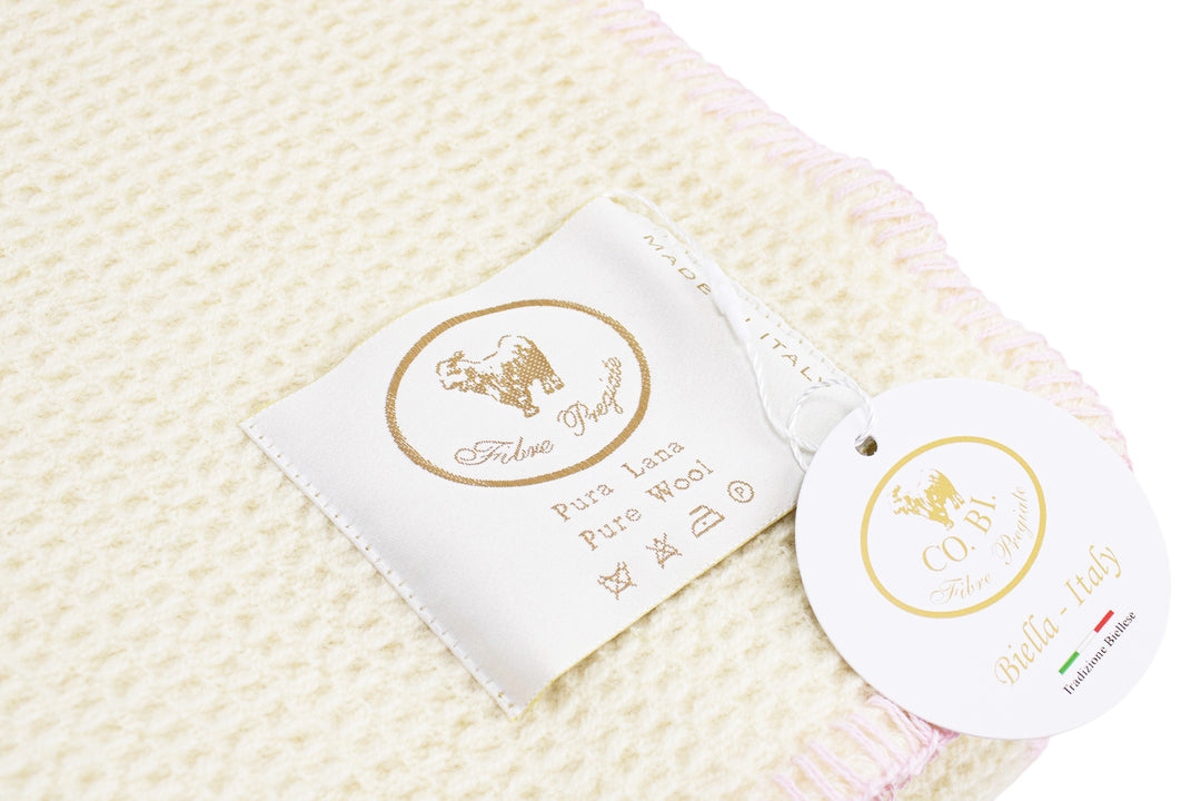 Particolare del plaid di pura lana a nido d'ape bianco e bordo rosa