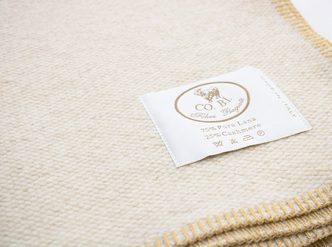 Particolare coperta beige con bordo senape di lana e cashmere