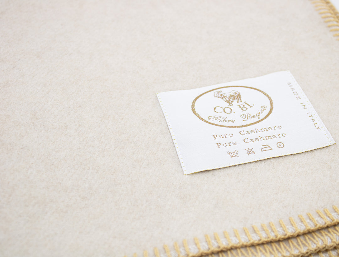 Particolare coperta di cashmere bianca con bordo senape